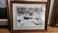 Full view of framed print showing winter landscape scene with snow, stream, and wolf.