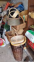 Wide view of assortment of stacked woven wicker baskets in various sizes and colors with some storage items visible in background