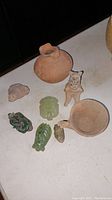 Full view of two bowls and six small figurines on a table, showing colors, materials, and approximate sizes.