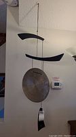 Full view of hanging gong wind chime showing wooden supports, gong disk and tags