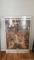 Photo showing full movie poster print of Raiders of the Lost Ark with Indiana Jones and other characters, wrapped in clear plastic.