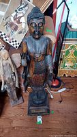 Frontal view of the large wooden Buddha statue showing full height and detailed carving on the face and robe.