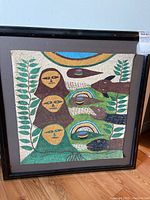 Full view of framed original hand-painted artwork on textured material with faces and animals.