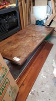Overall view of wood slab table top and carved pedestal base among storage items