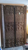 Two carved wooden door panels leaning against wall