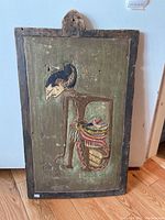 Full front view of carved wooden panel with stylized figure on green background