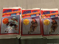 Three unopened 1991 Score NHL Hockey Card wax packs, Series 1, with promotional text and player graphics on the front of the packaging.