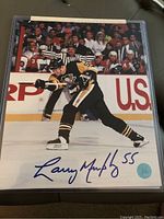 Front of autographed 8x10 photo showing Larry Murphy in action wearing Pittsburgh Penguins jersey with autograph in blue ink and number 55