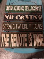 Photo of four wooden man cave signs with humorous sayings, showing distressed paint and rustic style.