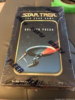 Photo of sealed Fleer Star Trek The Card Game booster box showing front art of USS Enterprise and sealed shrink wrap.