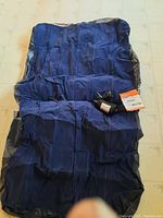 Deflated dark blue twin size air mattress laid out on floor with air pump and accessories on top.