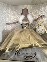 Millennial African American Barbie doll in original box wearing a gold glitter dress with white faux fur wrap and gold crown. Decorative ornament included.