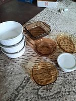 White Corning casseroles and brown Corning glass dishes on a carpet