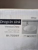 Close-up image of box label showing sink dimensions and material (vitreous china).