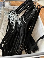 Top view showing black velvet no-slip clothes hangers with silver hooks placed inside the hamper