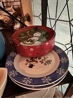 Stack of three holiday plates with snowman and snowflake designs