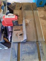 Router mounted on router table with adjustable fence and clamping knobs visible, showing dusty condition.