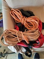 Two orange extension cords coiled on a chair
