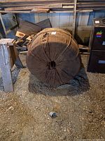 Full front view of the burlap-wrapped bale of rope on concrete floor with wooden planks behind