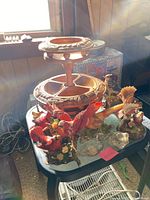 Photo showing two-tiered carved serving plate with bird and duck figurines placed around it on a table near a window.
