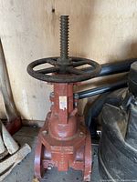 Full front view of vintage firemain gate valve showing red painted body, handwheel, and threaded stem.