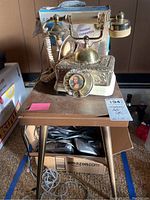 Mona Lisa themed rotary dial phone and wooden accent table on carpet floor with other boxes around