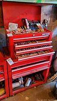 Two red Craftsman tool storage units stacked: top chest open, bottom cabinet visible on casters.