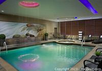 Indoor pool area with waterfall wall art, seating and hot tub