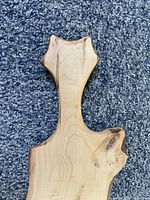 Close-up showing the unique handle shape and live edge of the natural wood charcuterie board.