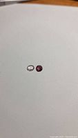 Two natural spinel gemstones, one deep red and one light-colored, shown side by side on a plain surface.