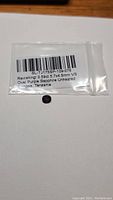 Photo of a small clear plastic bag containing a deep purple oval gemstone with a label describing it as a 0.59-0.69ct Oval Purple Sapphire, untreated, from Songea Tanzania, VS clarity.