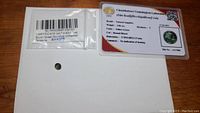 Natural sapphire gemstone laid on white paper with certification number visible in background