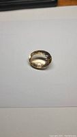 Oval cut natural golden citrine gemstone placed on white background showing side profile of the gem with clear facets and light golden transparent color.