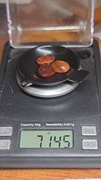 Three amber cabochons placed on a black dish on a digital scale displaying a total weight of 7.145 carats.