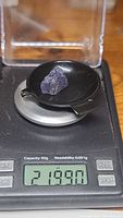 Tanzanite rough crystal placed on digital scale showing weight 21.99 carats.