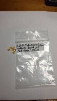 Parcel of seven small round cut golden yellow sapphires displayed on white background with plastic bag labeled with carat weight and size