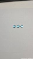 Three oval-cut Paraiba blue apatite gemstones laid side by side on a white background, showing overall size and shape.