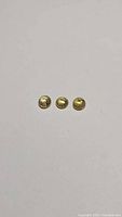Three small round yellow sphene gemstones placed on white background, showing top and side facets.