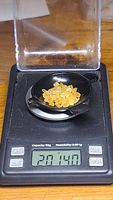 Weighing tray with small bright yellow sapphire crystals on a digital scale showing a weight of 20.14 carats.