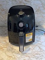 Front view of black Bella air fryer on countertop with handle and control knobs.