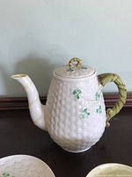 Front view of teapot showing basketweave body, shamrock decoration and lid