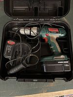 Black & Decker QuantumPro 18V cordless drill in hard plastic case with battery and charger cables tangled inside.