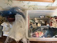 Wide view of tote showing white fabric, ribbons and plastic containers holding craft supplies