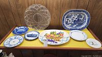 Full lot overview showing all platters and plates on a yellow surface against wood paneling