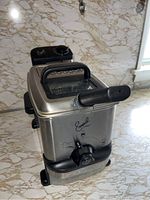 Front view of stainless steel Emeril by T-fal deep fryer with handle and oil drain valve visible.