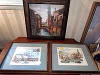 Photo showing all three framed artworks together: one upright painting of Venice canal scene and two matted prints side by side beneath it.