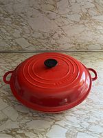 Top view of the red Le Creuset pan with lid on, showing round shape and handles.