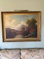 Full view of oil painting in gold frame with picture light mounted above wall