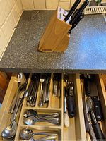 Drawer with organized stainless steel silverware: forks, spoons, serving spoons