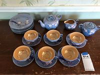 Full set arranged on table showcasing teapot, creamer, sugar bowl, cups, saucers, and plates with blue floral design.